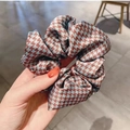 Detail showing hand holding the red and blue houndstooth pattern satin hair scrunchie - Blue Houndstooth