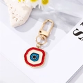 Detail eines bunten Evil-Eye-Anhängers aus Emaille an einem goldenen Schlüsselring - Rotes unregelmäßiges Auge