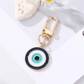 Detailed view of blue evil eye charm with gold spring clasp on a floral background - Black Blue Round Eye