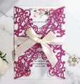 Detail of laser-cut glitter pink wedding invitation with beige satin ribbon on marble surface - Glitter Fuchsia