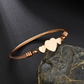 Rose gold braided cable wire bracelet featuring three polished heart charms on stone - Rose Gold