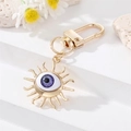 Portachiavi occhio greco a forma di sole dorato con strass su sfondo bianco moderno - Occhio Viola Sole