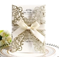 Dettaglio dell'invito di nozze oro glitterato con fiocco beige e carta perlata tagliata laser - Oro Chiaro Scintillante