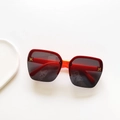 Macro detail of kids square sunglasses featuring orange red frame and golden H logo - Red