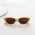 Detailed close-up of cream retro cat-eye sunglasses on a minimalist white ceramic tray - Light Yellow