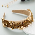 Dettaglio del cerchietto barocco con strass ambrati e tessuto in raso beige elegante - caffè