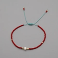 Handmade red beaded adjustable bracelet featuring a white pearl and blue woven cord - Red