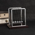 Classic Newton's Cradle with dark wooden base and five silver metal kinetic balls - Medium Square Red Base