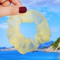 Detailed texture of yellow organza scrunchie hair tie held against a beach background - Yellow Plaid