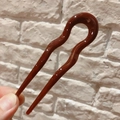 Detail showing smooth brown resin U-shaped hair pin with a polished glossy finish - Burgundy