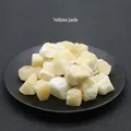 Natural raw yellow jade stone chunks displayed in a black bowl with a textured background - Yellow Jade