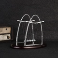 Newton's cradle with five silver metal balls and a dark wooden base on a grainy surface - Medium Sail Shape