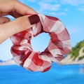 Detail of red and white gingham organza scrunchie held against a beach background - Large Dark Red Plaid