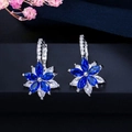 Vue macro de boucles d'oreilles fleur en cristal bleu et blanc sur support noir - Bleu