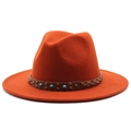 Detail of burnt orange fedora hat featuring a brown leather band with turquoise and studs - Rust red