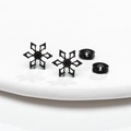 Macro detail of black snowflake stud earrings with butterfly backs on white surface - Black