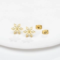 Minimalist gold snowflake stud earrings in stainless steel on white ceramic base - Gold