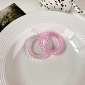 Detailed view of two gradient pink spiral hair ties on a white plate with aesthetic decor - Light Pink + Dark Pink
