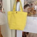 Detail of a bright yellow canvas tote bag featuring a bronze metal button closure - Ginger Yellow (With Snap Button)