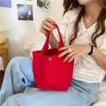 Detail of red canvas tote bag with magnetic closure held by a model in casual attire - Bright Red (With Snap Button)