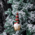 Weihnachtswichtel mit rot-grün gestreifter Strickmütze an einem verschneiten Tannenzweig - Rot-grüne Streifen