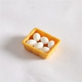 Detailed close-up of a miniature yellow egg tray with six tiny white eggs for dollhouse - Boxed White Eggs