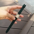 Detailed close-up of a square rose gold watch with dark green leather strap on a wrist - Green