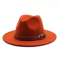 Close-up of orange wool fedora hat featuring a brown leather belt with silver buckle - Rust red