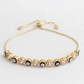 Detail of adjustable evil eye bracelet with cubic zirconia on white leather background - Black