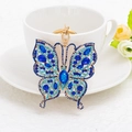 Blue butterfly rhinestone keychain with gold lobster clasp on a white coffee cup - Blue