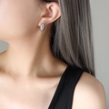 Minimalist silver oval stud earrings with polished metallic finish on female model - Steel