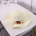 Close-up of beige straw sun hat with red cherry accents and wavy ruffled brim detail - M / Cream