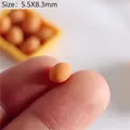 Macro shot of miniature dollhouse eggs sized 5.5x8.3mm held by fingers for scale - Single Brown Egg