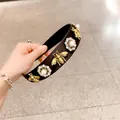 Detail eines Stoff-Haarreifs mit goldenen Bienen und Strass-Perlen-Blumen-Verzierungen - Schmale Krempe Biene