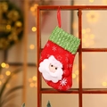 Calza di Natale con Babbo Natale 3D appesa al legno con luci festive soffuse sullo sfondo - Babbo Natale