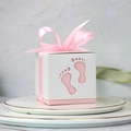 Pink and white hollow baby footprint candy boxes with silk ribbons on a gold-rimmed plate - Pink