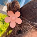Matte pink flower hair claw clip securing a ponytail on brown hair in natural sunlight - 7cm / Nude Pink