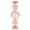 Makroansicht des rosa Emaille-Blumenarmbands und des glänzenden Zifferblatts der Quarzuhr - Rosa