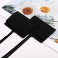 Detail of two black velvet jewelry pouches with flip lids and ties on a daisy card - 9*9cm / Black