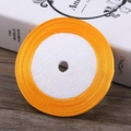 Bright orange satin ribbon roll for gift wrapping and hair accessories on a wooden desk - Gold