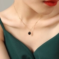 Elegante gouden kralenketting met ovale zwarte stenen hanger bij een vrouwelijk model - Kleine zwarte hanger / Goud