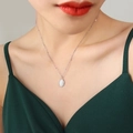 Zilveren kralenketting met ovale kattenoogsteen hanger gedragen door een vrouwelijk model - Kleine witte hanger / Staalkleur