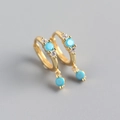 Vista macro de pendientes de aro dorados con piedras turquesas y colgantes redondos - Plata 925 / Dorado