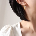Orecchini a goccia dorati con perle bianche indossati da una modella per lo stile chic - Oro