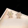 Elegant gold snowflake earrings with sparkling zircon stones on a premium jewelry gift box - Stud Earrings / Gold