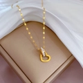 Detailopname van gouden hartjes hanger met kristallen cirkel en Love gravure op zijde - Goud