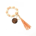 Détail de porte-clés en bois léopard avec pompon orange et disque gravé MAMA - Pêche