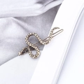 Fermaglio per capelli a forma di serpente in metallo bronzato con texture a scaglie su un libro - Oro Antico