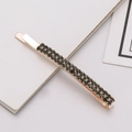 Dettaglio di un fermaglio in oro rosa con due file di strass grigi incastonati a griffe - grigio scuro