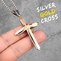 Silver and gold stainless steel cross pendant necklace held by hand against a wall - Silver-Gold Mix